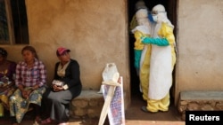 Healthcare workers enter a house where a baby suspected of dying of Ebola is, during the funeral in Beni, North Kivu Province of Democratic Republic of Congo, Dec. 18, 2018. 