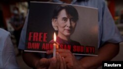 A demonstrator holds a placard and a candle during a protest against the military coup in Yangon, Myanmar, Feb. 16, 2021.