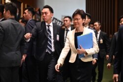 FILE - Hong Kong Chief Executive Carrie Lam, right, walks past protesting pro-democracy lawmakers as she arrives for a question and answer session in the Legislative Council in Hong Kong, Oct. 17, 2019.