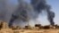 FILE - A man walks while smoke rises above buildings after aerial bombardment, during clashes between the paramilitary Rapid Support Forces and the army in Khartoum North, May 1, 2023.