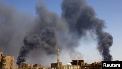 FILE—A man walks while smoke rises above buildings after aerial bombardment, during clashes between the paramilitary Rapid Support Forces and the army in Khartoum North, Sudan, May 1, 2023.