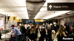 Los viajeros que usan mascarillas protectoras para prevenir la propagación de la enfermedad por coronavirus recuperan su equipaje en el aeropuerto de Denver, Colorado, EE. UU., el 24 de noviembre de 2020.