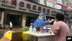 FILE - A medical worker wearing protective gear conducts COVID-19 tests on residents in Shanghai, China, April 10, 2022.