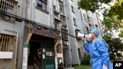 A volunteer uses a megaphone to talk to residents at an apartment building in Shanghai, China, April 12, 2022. (Xinhua News Agency via AP)
