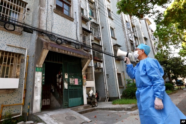 Seorang sukarelawan menggunakan megafon untuk berbicara dengan warga di sebuah gedung apartemen di Shanghai, China, 12 April 2022. (Xinhua News Agency via AP)