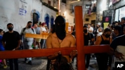 Un penitente lleva una cruz y un látigo con clavos mientras camina en una procesión de Semana Santa en Taxco, México, el jueves 14 de abril de 2022. (Foto Eduardo Verdugo / AP)