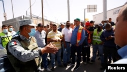 지난 12일 멕시코 시우다드후아레스에서 미국 텍사스주로 연결되는 무역로 '제로니모-산타 테레사 국제다리'를 가로막은 멕시코 트럭 운전사들과 현지 방위대원이 대화하고 있다.