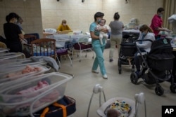 Nannies take care of newborn babies in a basement converted into a nursery in Kyiv, Ukraine, March 19, 2022. Nineteen babies were born to surrogate mothers, with their biological parents still outside the country due to Russia's invasion of Ukraine.