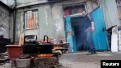 Un residente local cocina comida en un incendio fuera de un edificio dañado durante el conflicto entre Ucrania y Rusia en la ciudad portuaria sureña de Mariuúpol, Ucrania, el 18 de abril de 2022.