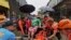 In this handout photo provided by the Philippine Coast Guard, rescuers evacuate a resident to safer ground at Abuyog, Leyte province, central Philippines on Sunday April 10, 2022. (Philippine Coast Guard via AP)