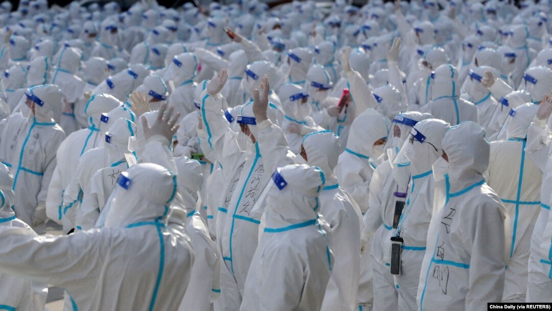 Petugas medis dengan pakaian APD melambai ke arah warga Changchun saat upacara perpisahan sebelum kembali ke Meihekou, tempat mereka membantu menangani wabah COVID-19 di Changchun, China, 12 April 2022. (Foto: via Reuters)