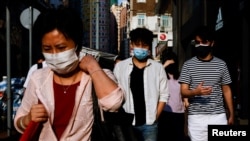 Pejalan kaki mengenakan masker saat berjalan di kawasan Wan Chai, Hong Kong, di tengah pandemi COVID-19, 14 April 2022.