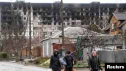 13일 우크라이나 남동부 항구도시 마리우폴 주민들이 폭격에 파괴된 아파트 앞을 지나고 있다.