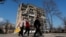 Local residents walk past an apartment building damaged during Russia's aggression against Ukraine, in Mariupol, Ukraine, April 15, 2022.