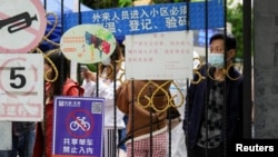 上海封城后居民在关闭的小区大门后等候递送的食物。（2022年4月13日）