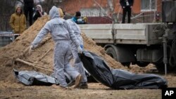 TƯ LIỆU: Những người mặc đồ bảo hộ khai quật thi thể của thường dân bị giết trong thời gian Nga chiếm đóng ở Bucha, ngoại ô Kyiv, Ukraine, ngày 13 tháng 4 năm 2022.