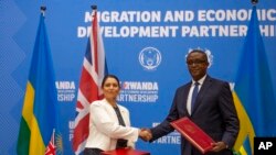 Britain's Home Secretary Priti Patel, (L) shakes hands with Rwanda's Minister of Foreign Affairs Vincent Biruta, (R) after signing the immigration deal in Kigali, Rwanda Thursday, April 14, 2022.