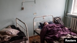 A woman lies in a bed at a delapidated hospital in the town of Severodonetsk, in Ukraine's war-ravaged Luhansk region, April 14, 2022.
