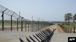 This picture taken on Aug. 15, 2021 shows a barbed wire wall near a police checkpoint, two kilometres from "Friendship Bridge" over the Amu Darya river, which separates Uzbekistan and Afghanistan near Termez.