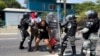 Efectivos de la Guardia Nacional de México detienen a una mujer migrante en Tapachula, México, mientras otros pasan corriendo, el 1 de abril de 2022.