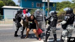 Efectivos de la Guardia Nacional de México detienen a una mujer migrante en Tapachula, México, mientras otros pasan corriendo, el 1 de abril de 2022.