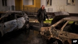 A man looks at his burned car after a Russian attack in Kharkiv, Ukraine, April 15, 2022.