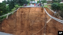 Watu wamekwama kuvuka wakiwa mbele ya daraja ambalo lilichukuliwa na maji baada ya mvua na mafuriko yaliyoendelea huko Ntuzuma, nje ya Durban, Afrika Kusini. (Picha na AP)>