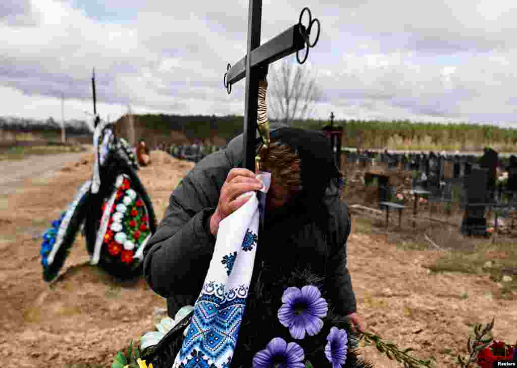 Galina Bondar, 63, who said her son, Olexander Bondar, 32, a territorial defense member, was killed by Russian troops, kisses the plaque bearing his name at his grave at the cemetery in Bucha, Ukraine.