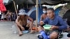 Migrantes cubanos comen en un campamento, instalado por cubanos varados en South Drain mientras esperan el servicio de ferry de Surinam a Guyana, mientras intentan llegar a Estados Unidos, en Nickerie, Surinam, el 11 de diciembre de 2020.