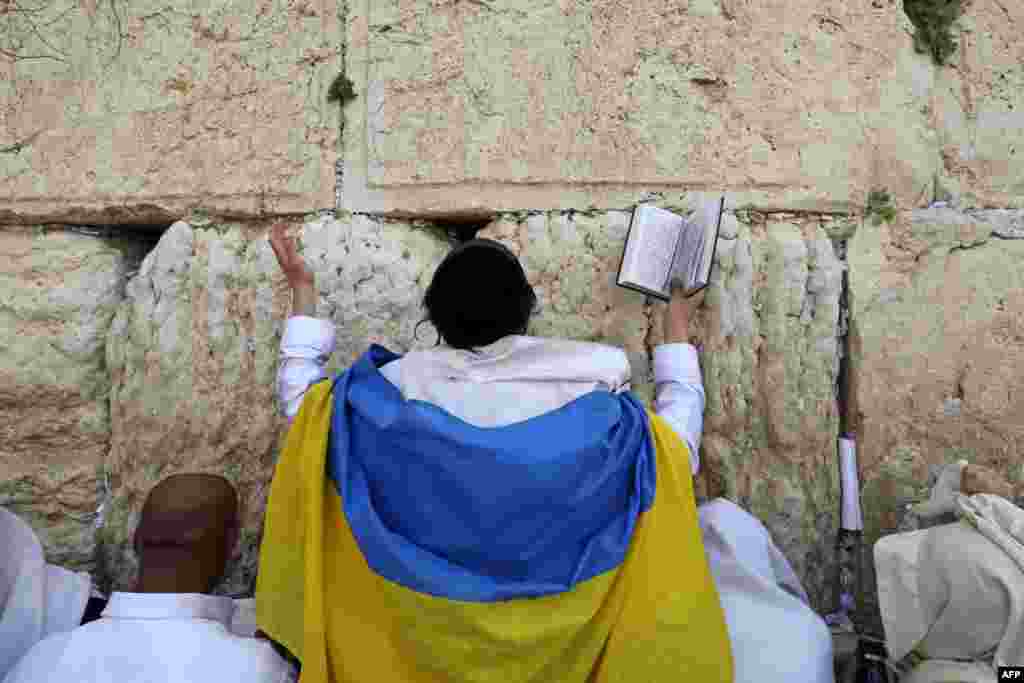 A Jewish worshipper covered in a Ukranian flag takes part in the Cohanim prayer (priest&#39;s blessing) during the Passover holiday at the Western Wall in Jerusalem&#39;s Old City.