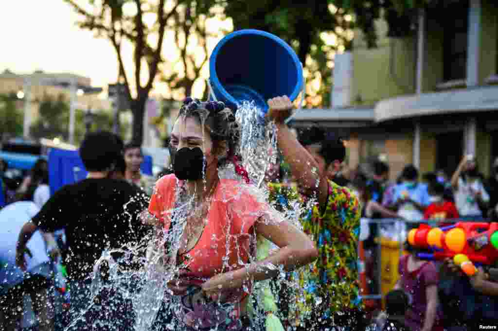 A man pours water on a woman during the Songkran holiday which marks the Thai New Year in Bangkok, Thailand, April 13, 2022.