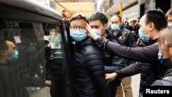 FILE - Stand News acting chief editor Patrick Lam, one of the six people arrested "for conspiracy to publish seditious publication" according to Hong Kong's Police National Security Department, is escorted by police after the police searched his office, Dec. 29, 2021.