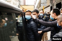 FILE - Stand News acting chief editor Patrick Lam, one of the six people arrested "for conspiracy to publish seditious publication" according to Hong Kong's Police National Security Department, is escorted by police after the police searched his office in Hong Kong, China, Dec. 29, 2021.