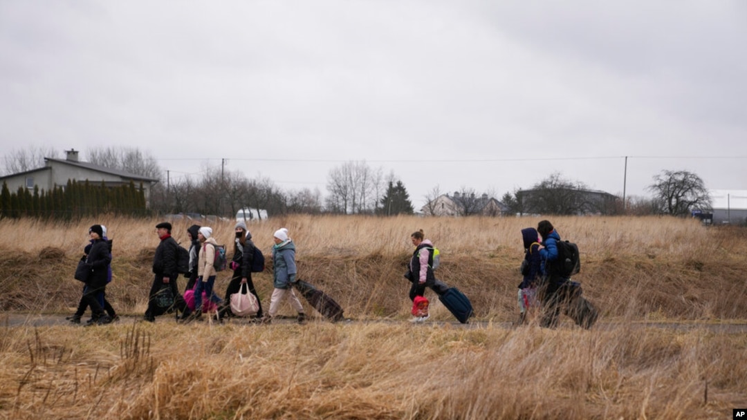 FILE - Orang-orang berjalan dengan barang-barang mereka di perbatasan Medyka, Polandia, saat melarikan diri dari Ukraina, 5 Maret 2022.