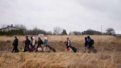 FILE - Orang-orang berjalan dengan barang-barang mereka di perbatasan Medyka, Polandia, saat melarikan diri dari Ukraina, 5 Maret 2022.