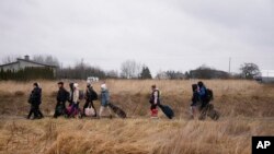 People walk with their belongings, as they flee Ukraine, at the border crossing in Medyka, Poland, March 5, 2022. 