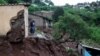 Une femme se tient à sa porte d'entrée après que de fortes pluies ont causé des dégâts d'inondation à KwaNdengezi, Durban, Afrique du Sud.