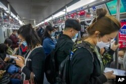 Penumpang yang memakai masker wajah di dalam kereta bawah tanah. (Foto: AP)