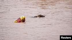 A search and rescue team member looks for bodies with the help of a dog, following torrential rains that triggered floods and mudslides, in Umbumbulu, near Durban, South Africa, April 18, 2022.