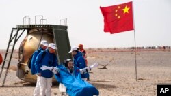 Astronaut China Ye Guangfu duduk di luar kapsul yang membawanya kembali ke bumi dan mendarat di lokasi pendaratan Dongfeng, pada 16 April 2022. Ia baru saja menyelesaikan misi antariksa berawak Shenzhou-13. (Foto: Xinhua via AP/Cai Yang)