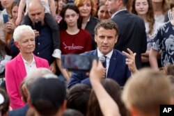 FILE - French President and centrist presidential candidate for reelection Emmanuel Macron speaks with residents about security in Chatenois, France, April 12, 2022.