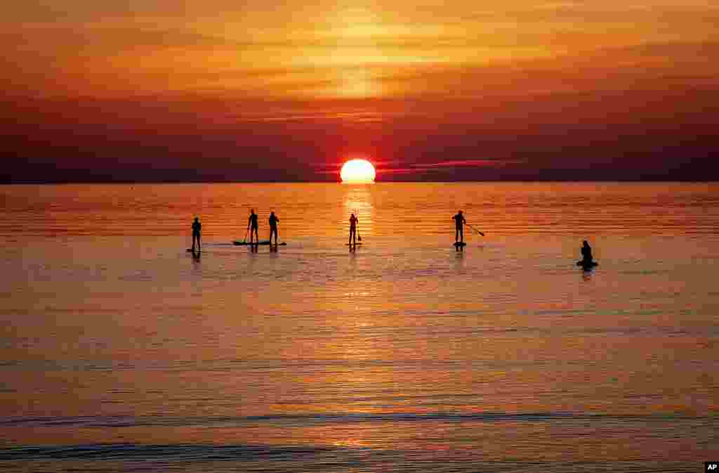 Paddle boarders visit the calm Baltic Sea in Timmendorfer Strand northern Germany as the sun rises on a cold Monday morning.
