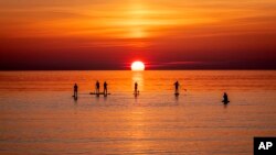 Paddle boarders visit the calm Baltic Sea in Timmendorfer Strand northern Germany as the sun rises on a cold Monday morning.