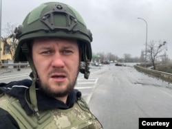 Ukrainian investigative reporter Denis Kazansky with destroyed civilian cars in the background in the town of Bucha, near Kyiv, April 4, 2022. (Denis Kazansky)