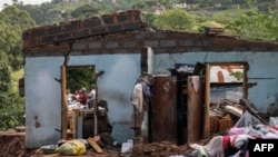 FILE: Neighbors stand next to the remains of a house at KwaNdengezi township outside Durban, April 15, 2022 where 10 people are reported missing after their homes were swept away in devastating rains and flooding. 