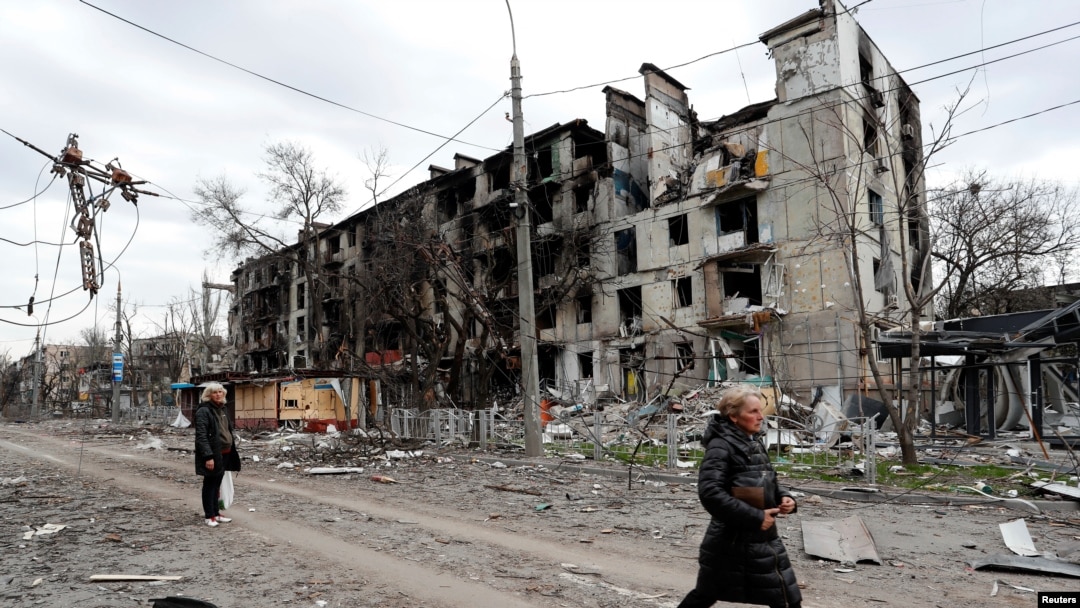 Ljudi prolaze pored stambene zgrade, koja je uništena u južnom lučkom gradu Mariupolju u Ukrajini tokom ruske invazije na Ukrajinu, 18. aprila 2022. 