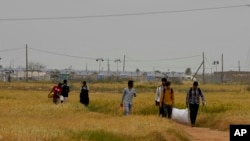 Para migran berjalan di dekat pusat penerimaan darurat Pournara di Kokkinotrimithia, di luar ibu kota Nicosia, Siprus, Senin, 18 April 2022. (AP/Petros Karadjias)