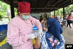 Seorang nakes (kiri) memberikan vaksin booster COVID-19 Pfizer di Jakarta, 29 Maret 2022. (Foto: ADEK BERRY / AFP)