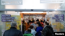 People stand in line to buy postage stamps showing a Ukrainian service member's obscene reaction to a Russian warship at the headquarters of the Ukrainian postal service in Kyiv, April 14, 2022.