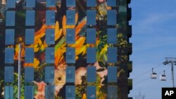 An apartment block is decked out in huge prints of flowers and towers over a newly built cable car at the once-a-decade Dutch horticultural exhibition called Floriade in Almere, Netherlands, Monday, April 11, 2022, that aims to showcase ways of making urb